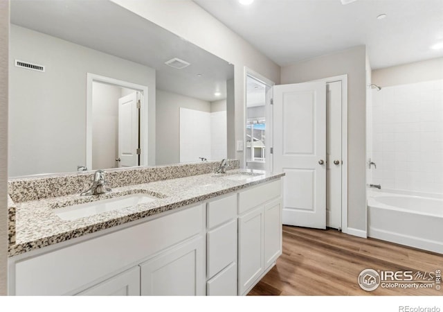 bathroom featuring dual bowl vanity, wood-type flooring, and shower / tub combination