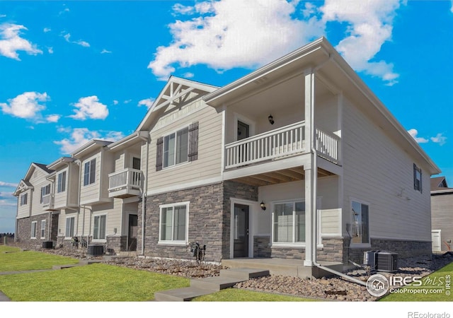 rear view of property with a yard, central AC, and a balcony