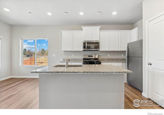 kitchen featuring light stone countertops, light hardwood / wood-style flooring, stainless steel appliances, white cabinetry, and sink