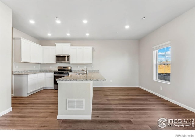 kitchen with dark hardwood / wood-style flooring, light stone countertops, white cabinetry, and stainless steel appliances