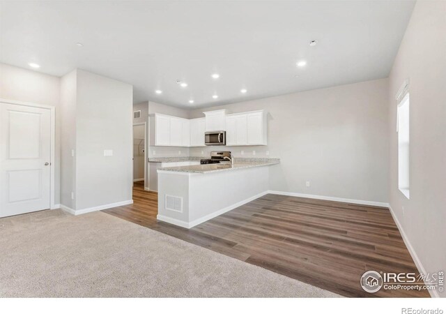 kitchen with wood-type flooring, range, white cabinetry, and kitchen peninsula