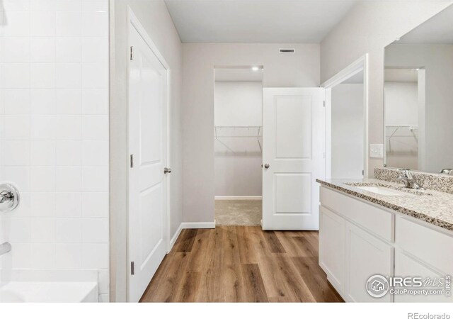 bathroom with hardwood / wood-style floors, vanity, and shower / washtub combination