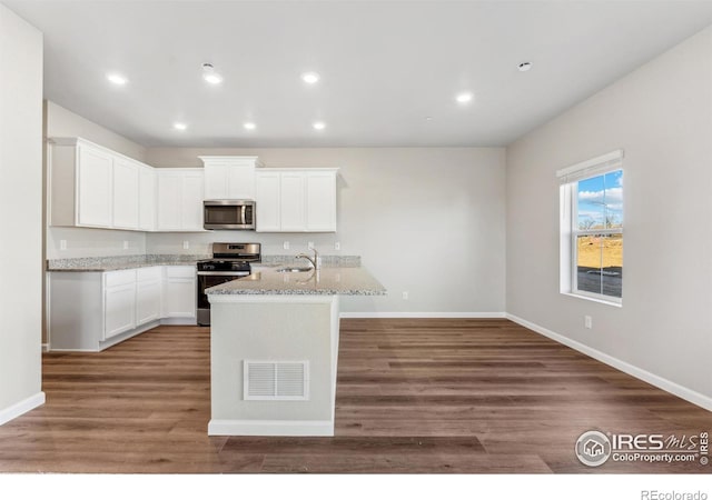 kitchen with white cabinetry, stainless steel appliances, dark hardwood / wood-style floors, and light stone countertops