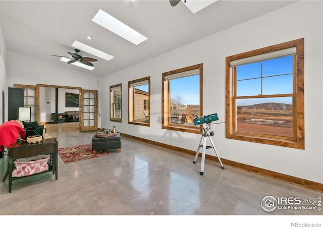 interior space featuring ceiling fan, vaulted ceiling with skylight, and french doors