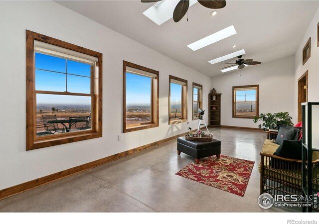 living room featuring concrete flooring, lofted ceiling with skylight, and ceiling fan