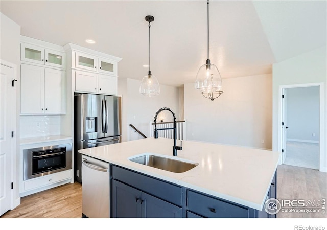 kitchen with decorative light fixtures, white cabinetry, appliances with stainless steel finishes, sink, and blue cabinets