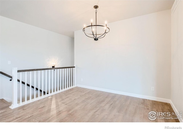 unfurnished room featuring a chandelier and light hardwood / wood-style floors