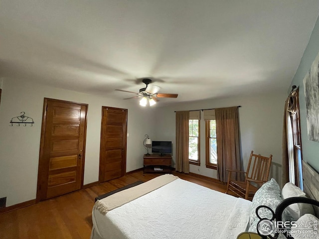 bedroom with two closets, wood-type flooring, and ceiling fan