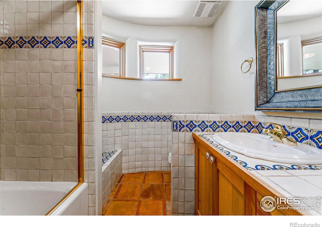 bathroom with tile patterned floors, vanity, tile walls, and tiled shower / bath combo