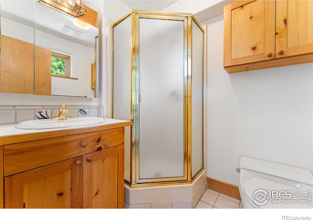 bathroom featuring tile patterned floors, vanity, a shower with shower door, and toilet