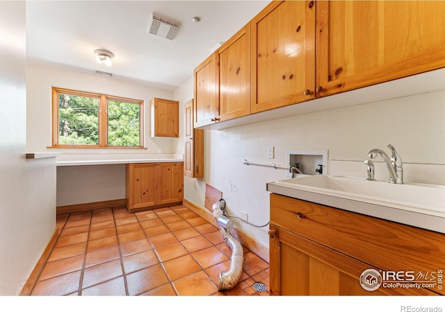 interior space featuring washer hookup, cabinets, light tile patterned floors, and sink