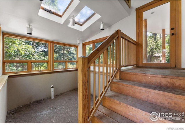 stairway with lofted ceiling with skylight and plenty of natural light