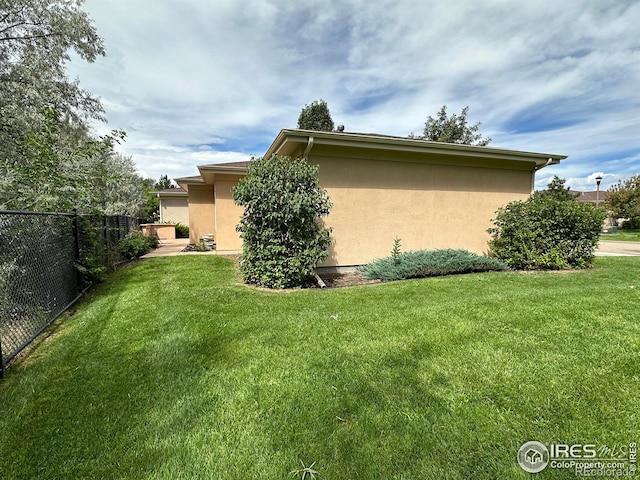 view of property exterior featuring a yard, fence, and stucco siding