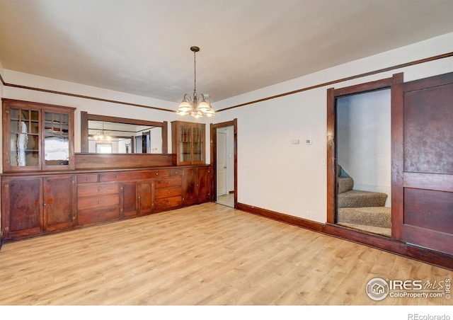 empty room featuring a chandelier and light hardwood / wood-style floors