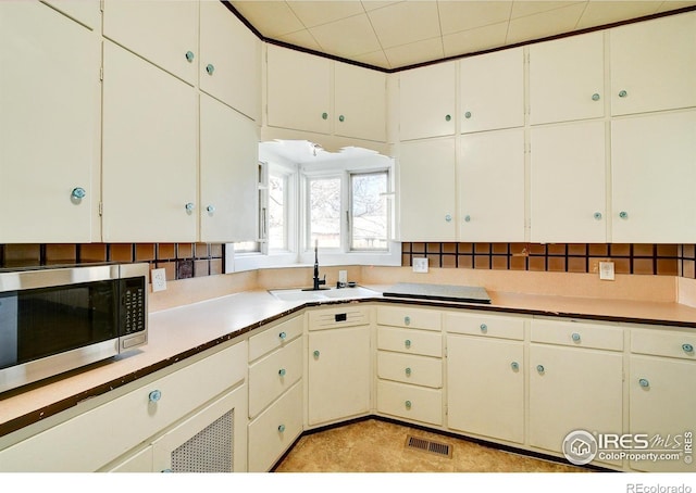 kitchen with light tile floors, white cabinetry, and sink