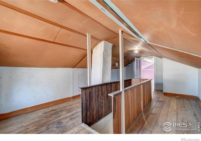 additional living space featuring vaulted ceiling and light wood-type flooring