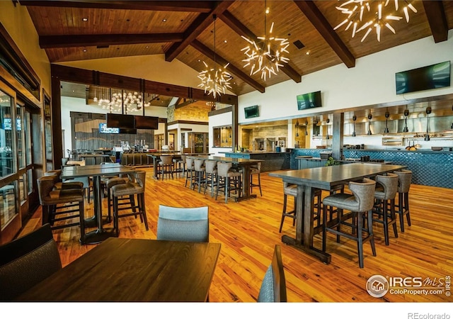 dining area featuring an inviting chandelier, beamed ceiling, high vaulted ceiling, and wooden ceiling