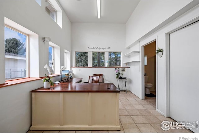 interior space with a high ceiling, light tile patterned flooring, and kitchen peninsula