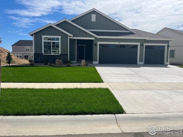 craftsman house with board and batten siding, concrete driveway, a front yard, an attached garage, and roof with shingles