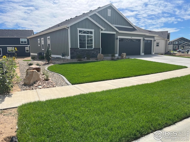 view of front of house featuring a front lawn, driveway, stone siding, board and batten siding, and an attached garage