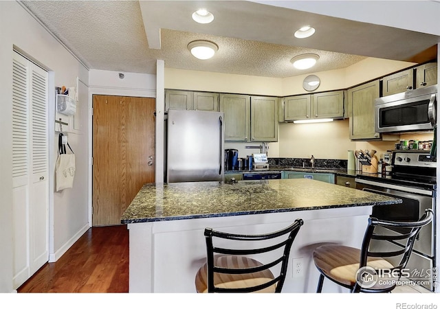 kitchen featuring a kitchen bar, appliances with stainless steel finishes, dark hardwood / wood-style floors, and a textured ceiling