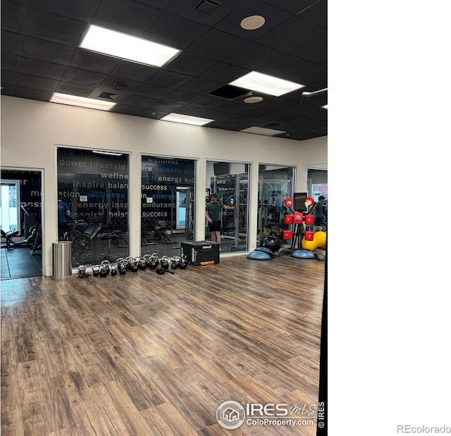 exercise room with wood-type flooring and a paneled ceiling