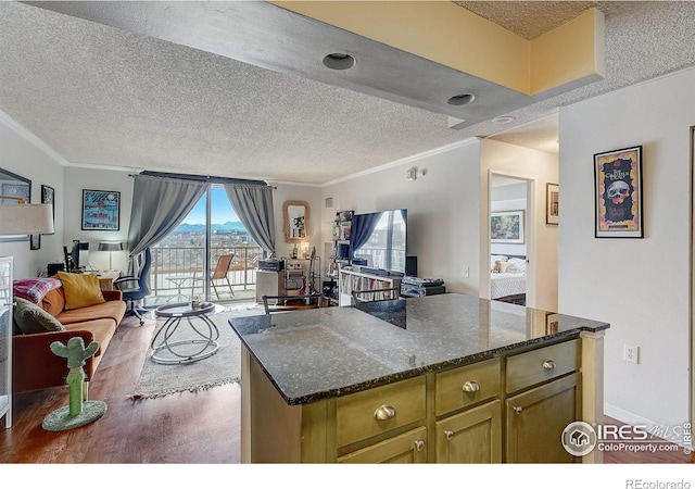 kitchen with a textured ceiling, dark wood-type flooring, a center island, and ornamental molding