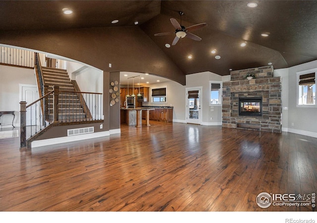 unfurnished living room with dark wood-type flooring, ceiling fan, high vaulted ceiling, and a fireplace