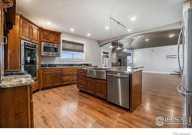 kitchen featuring stainless steel appliances, hardwood / wood-style floors, sink, pendant lighting, and a textured ceiling