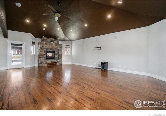 unfurnished living room featuring dark wood-type flooring, a stone fireplace, high vaulted ceiling, and ceiling fan