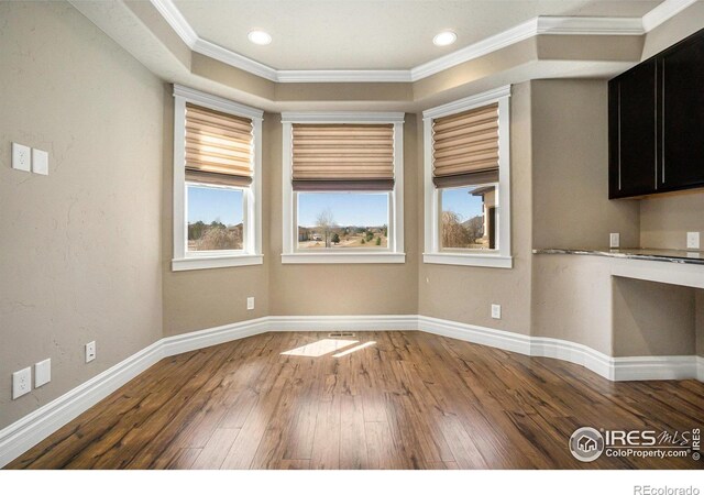 unfurnished dining area with crown molding, a healthy amount of sunlight, and wood-type flooring