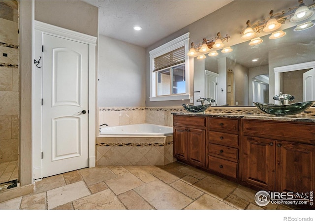 bathroom featuring vanity and tiled tub