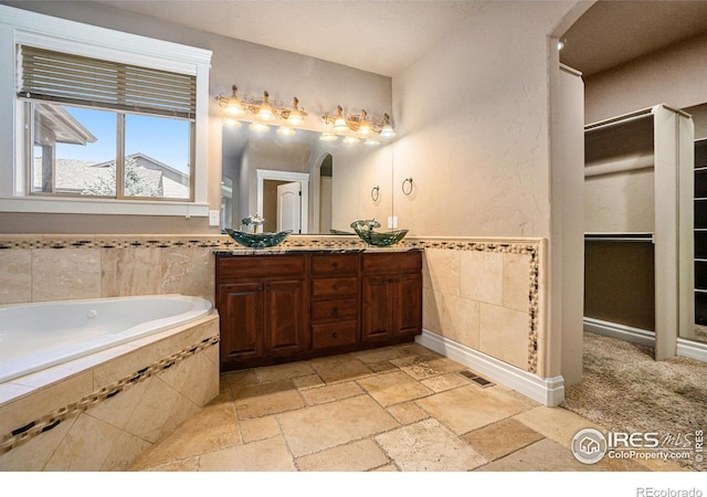 bathroom with vanity and a relaxing tiled tub