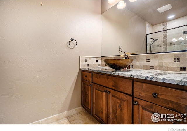 bathroom featuring vanity, tasteful backsplash, and a shower with shower door