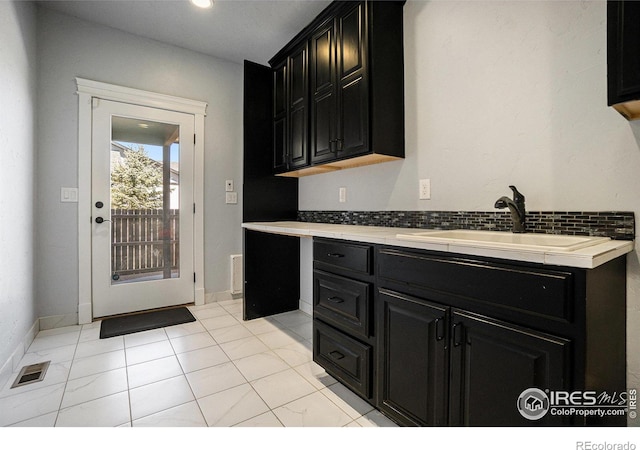 kitchen featuring sink, light tile patterned floors, and backsplash