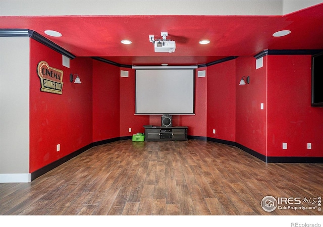 cinema room with ornamental molding and dark hardwood / wood-style flooring