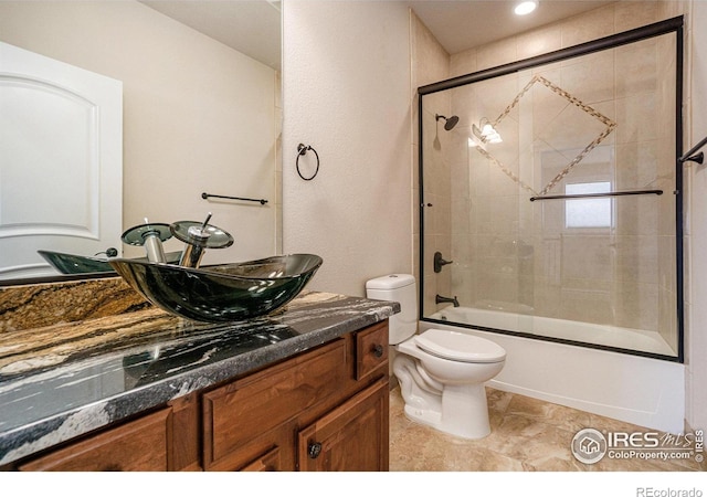 full bathroom with toilet, bath / shower combo with glass door, and vanity