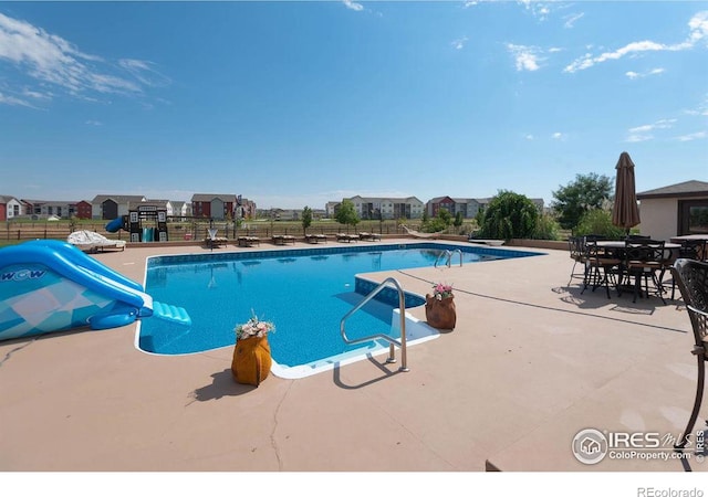 view of pool with a patio, a water slide, and a diving board