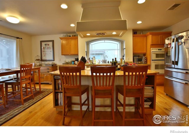 kitchen featuring a wealth of natural light, a kitchen island, light hardwood / wood-style floors, and appliances with stainless steel finishes