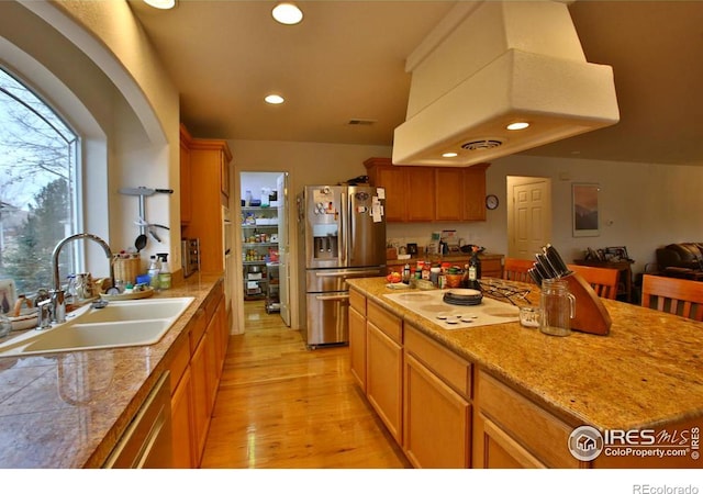 kitchen with a kitchen island, sink, exhaust hood, light hardwood / wood-style floors, and stainless steel appliances