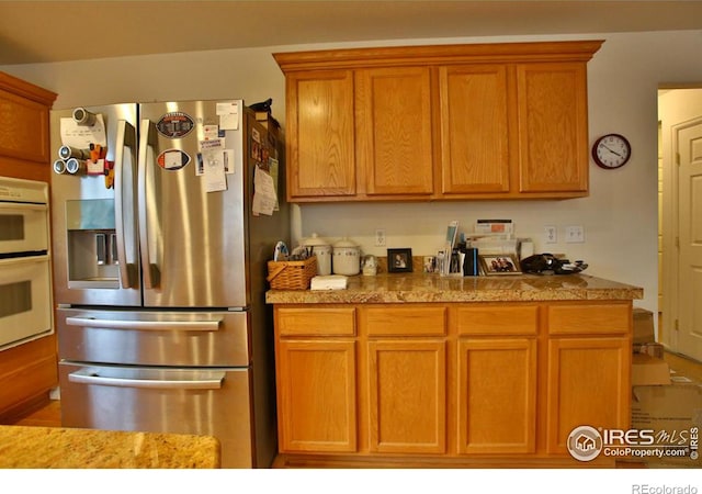 kitchen with double oven and stainless steel fridge with ice dispenser