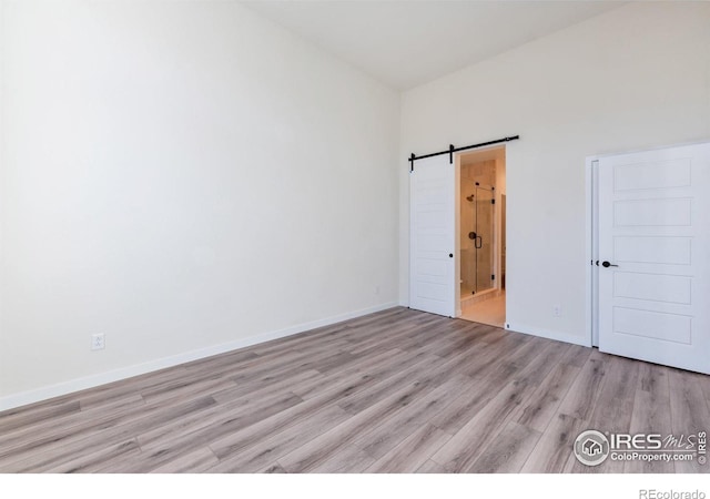 spare room featuring a barn door and light wood-type flooring