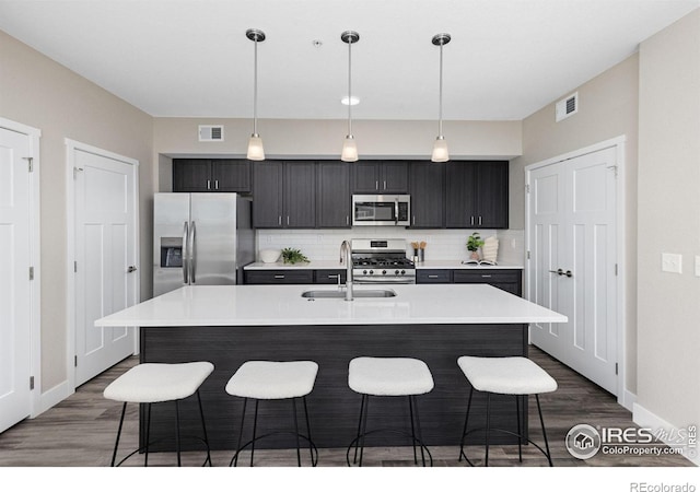 kitchen with a center island with sink, appliances with stainless steel finishes, sink, and pendant lighting