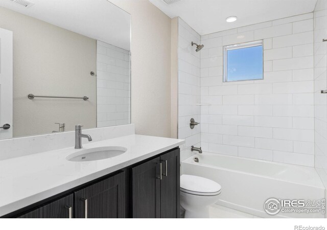 full bathroom featuring tiled shower / bath, vanity, and toilet