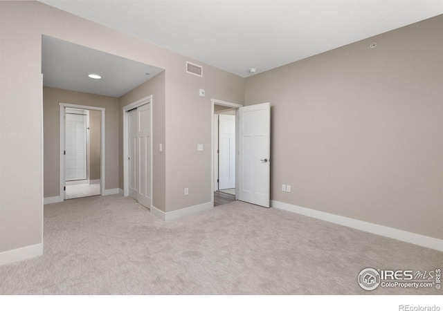 unfurnished bedroom featuring light colored carpet and a closet