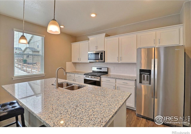 kitchen with dark hardwood / wood-style flooring, appliances with stainless steel finishes, tasteful backsplash, a kitchen island with sink, and sink