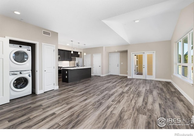 unfurnished living room featuring stacked washing maching and dryer, wood-type flooring, and lofted ceiling