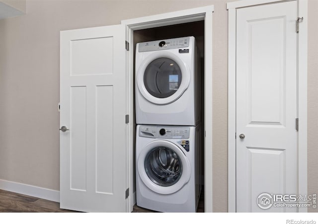 laundry area featuring dark hardwood / wood-style flooring and stacked washer and clothes dryer