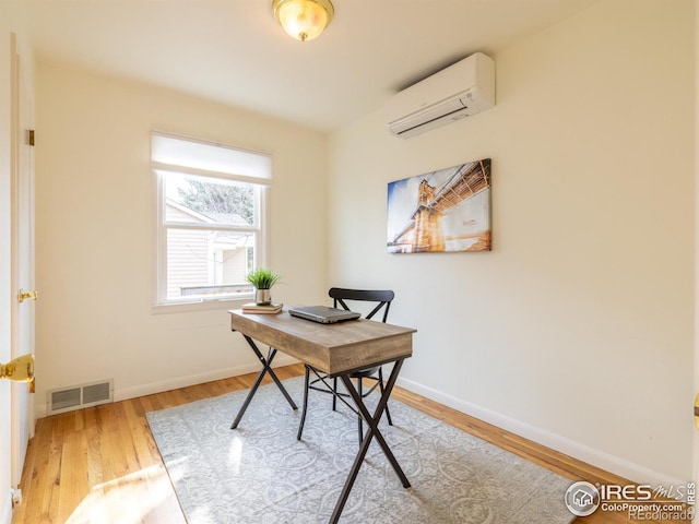 home office featuring hardwood / wood-style floors and a wall unit AC