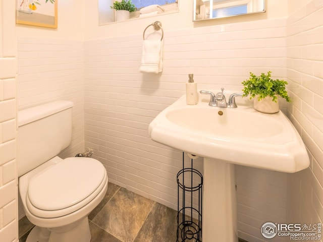 bathroom featuring toilet and tile walls